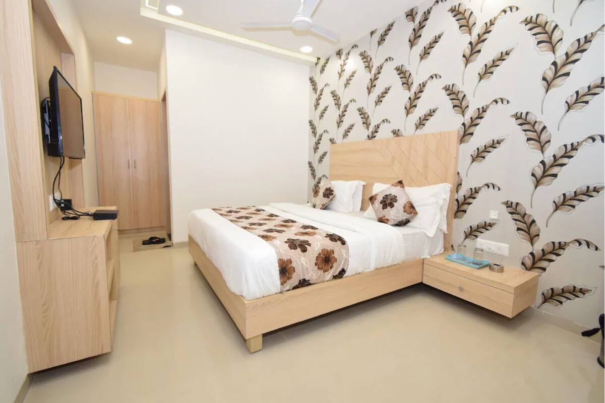 Un dormitorio con cama, televisor, armario y mesita de noche.