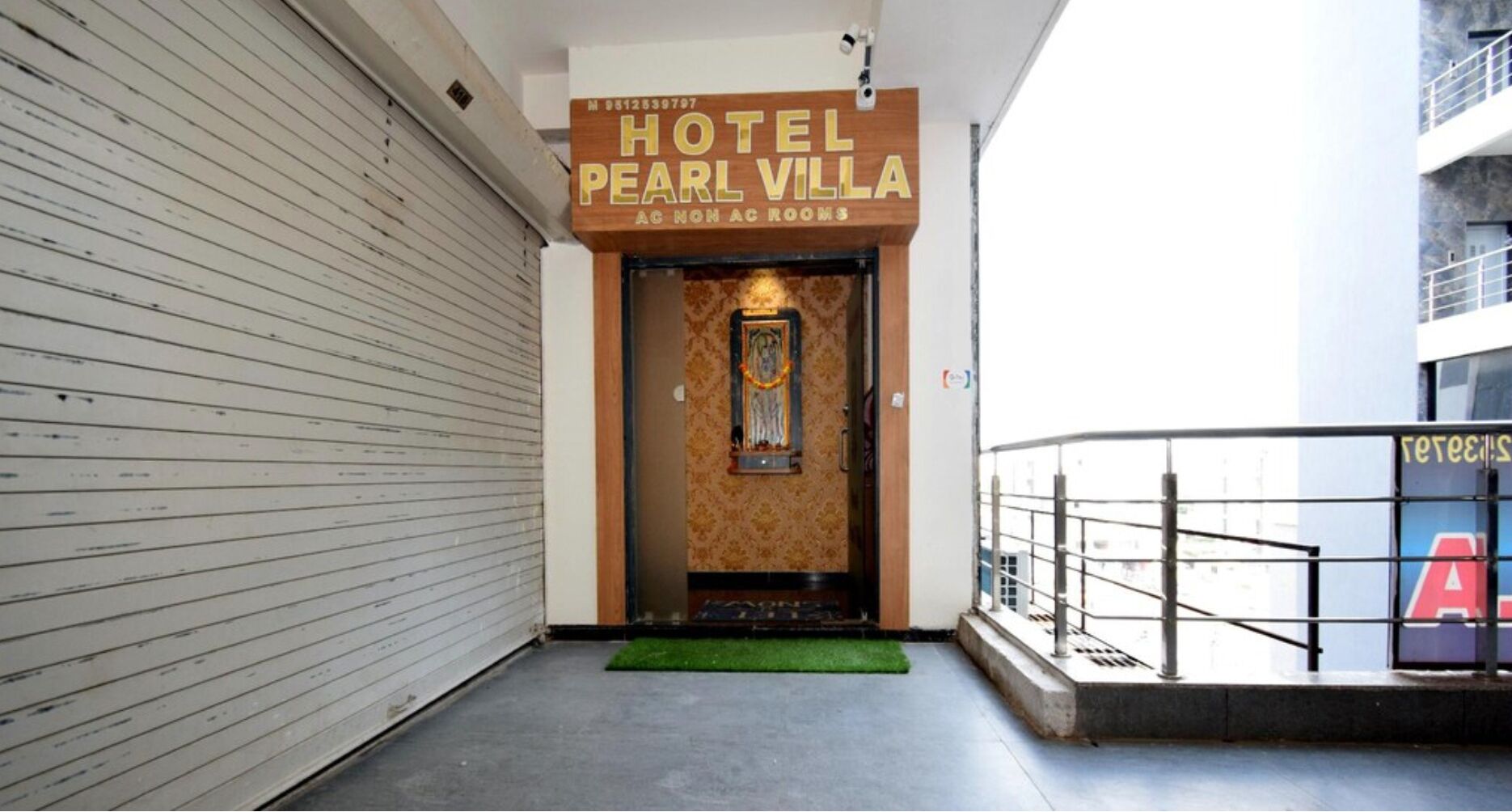 A hotel entrance with a sign reading "HOTEL PEARL VILLA AC NON AC ROOMS".