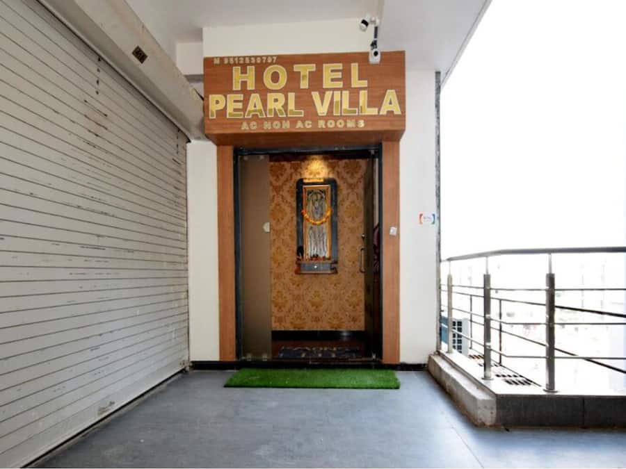 A hotel entrance with a sign reading "HOTEL PEARL VILLA AC NON AC ROOMS".
