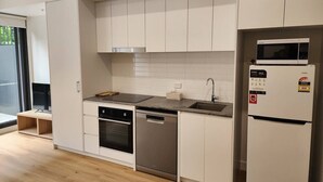 A modern kitchen with white cabinets, a built-in oven, dishwasher, and a refrigerator.