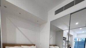 A modern hotel room with a large bed, a mirror, and a view of the adjacent room.
