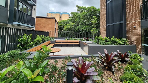 A rooftop garden with seating, surrounded by buildings.