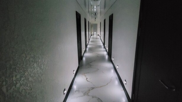 Un long couloir étroit doté d’un sol en marbre et d’un éclairage encastré.