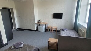 Une chambre avec deux lits, un bureau, une chaise, une télévision et une fenêtre.