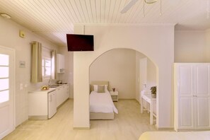 A bedroom with a bed, a desk, a chair, a TV, and a wardrobe.