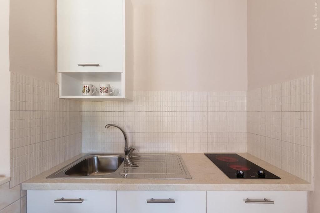 A kitchen with a sink, a stove, and a cabinet above the sink.
