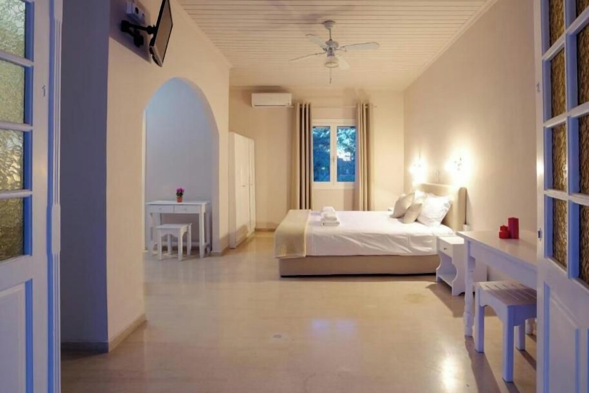 Un dormitorio con cama, mesita de noche y escritorio con silla.