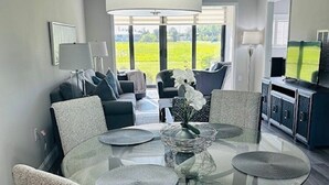 Un comedor moderno con una mesa de vidrio, sillas tapizadas grises y un florero central.