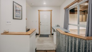 A narrow hallway with a wooden counter, a door, and a window with curtains. - Welcome to The Baker House Retreat - The Ranch House and The Bunk House (Maple Falls)