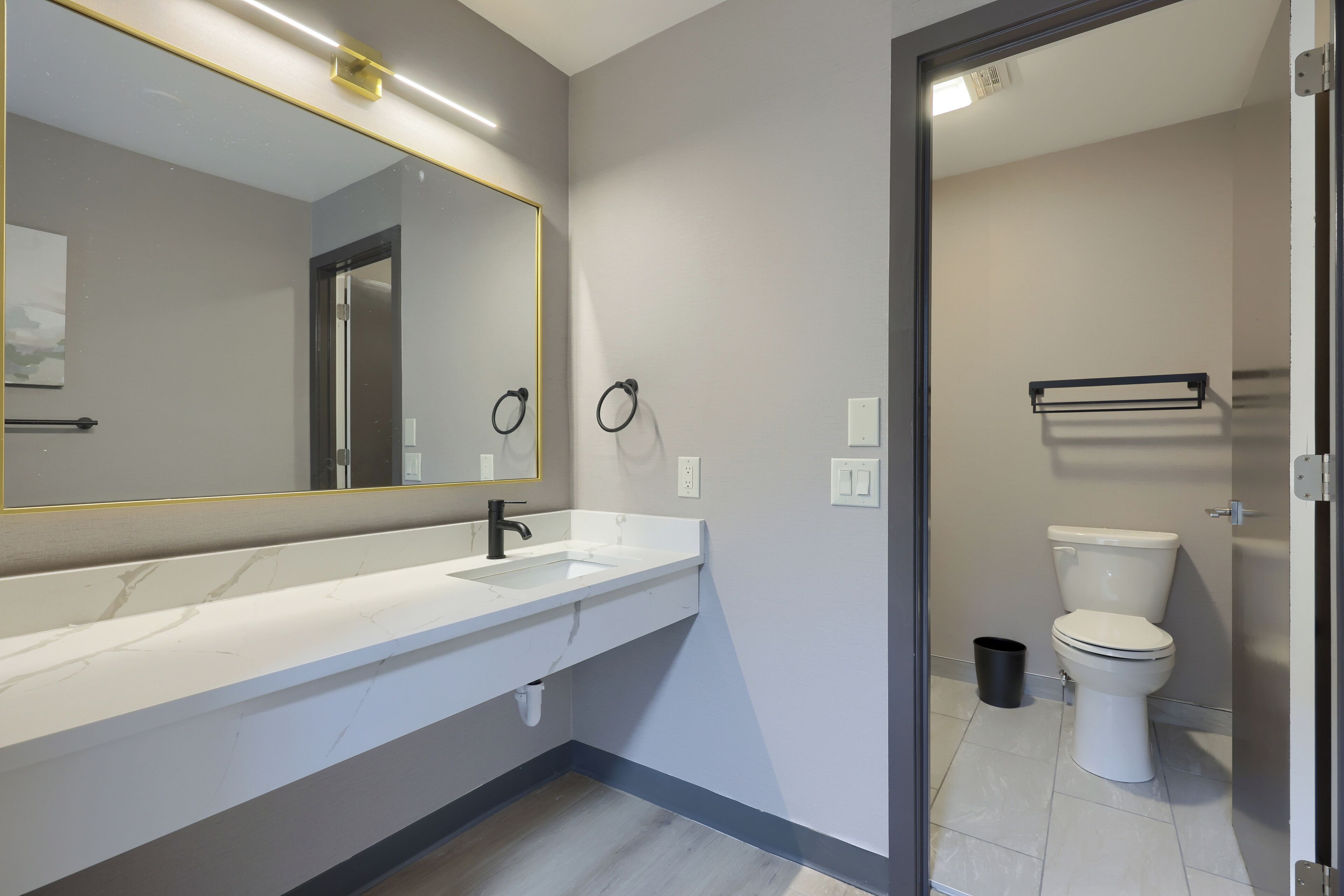 A modern bathroom with a white sink, a large mirror, and a toilet.