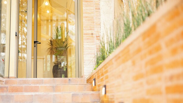 A staircase leading to a glass door entrance with a brick wall on one side. - Moabi Hotel (Medellín)