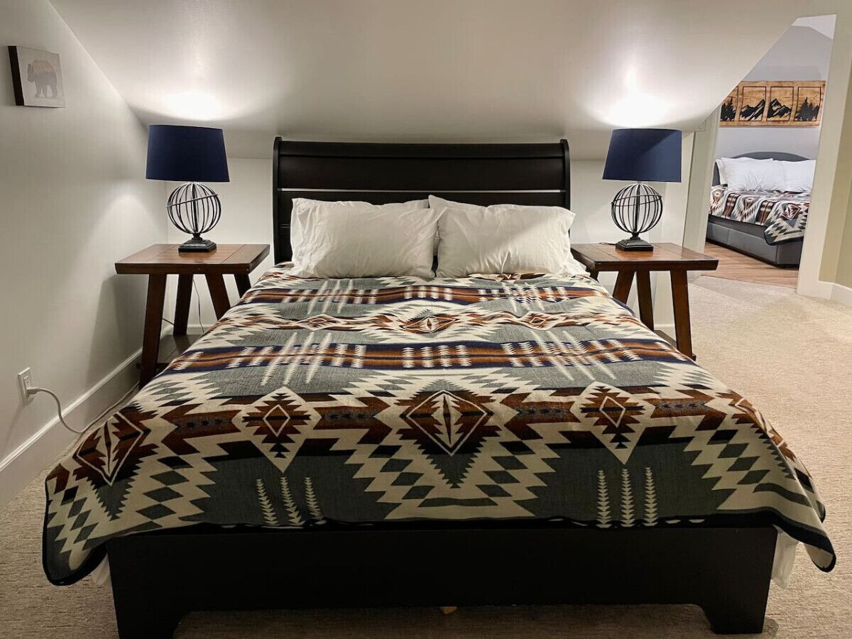 Een bed met een gebloemd dekbed, twee bedlampen en een hoofdbord.