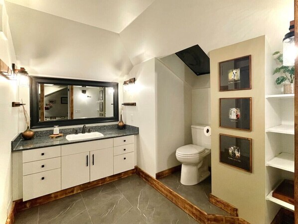 Een badkamer met een grote spiegel, een wastafel, een toilet en lijstwerken aan de muur.
