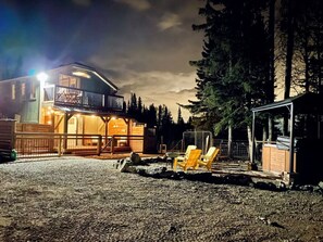 Een lodge met een overdekt terras, buitenmeubels en een grindpad.