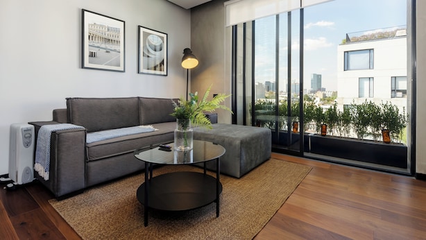 A modern living room with a grey sofa, a glass coffee table, and a large window offering a city view. - Zacatecas 4 by Wynwood House  (Mexico City)