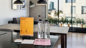 A reception desk with a welcome sign, two water bottles, and a pink welcome card. - Zacatecas 4 by Wynwood House  (Mexico City)