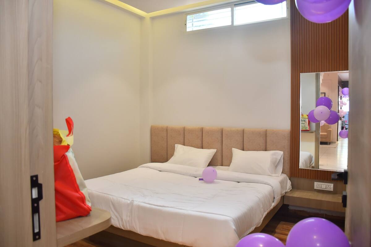 Un dormitorio con cama, mesita de noche, espejo y ventana.