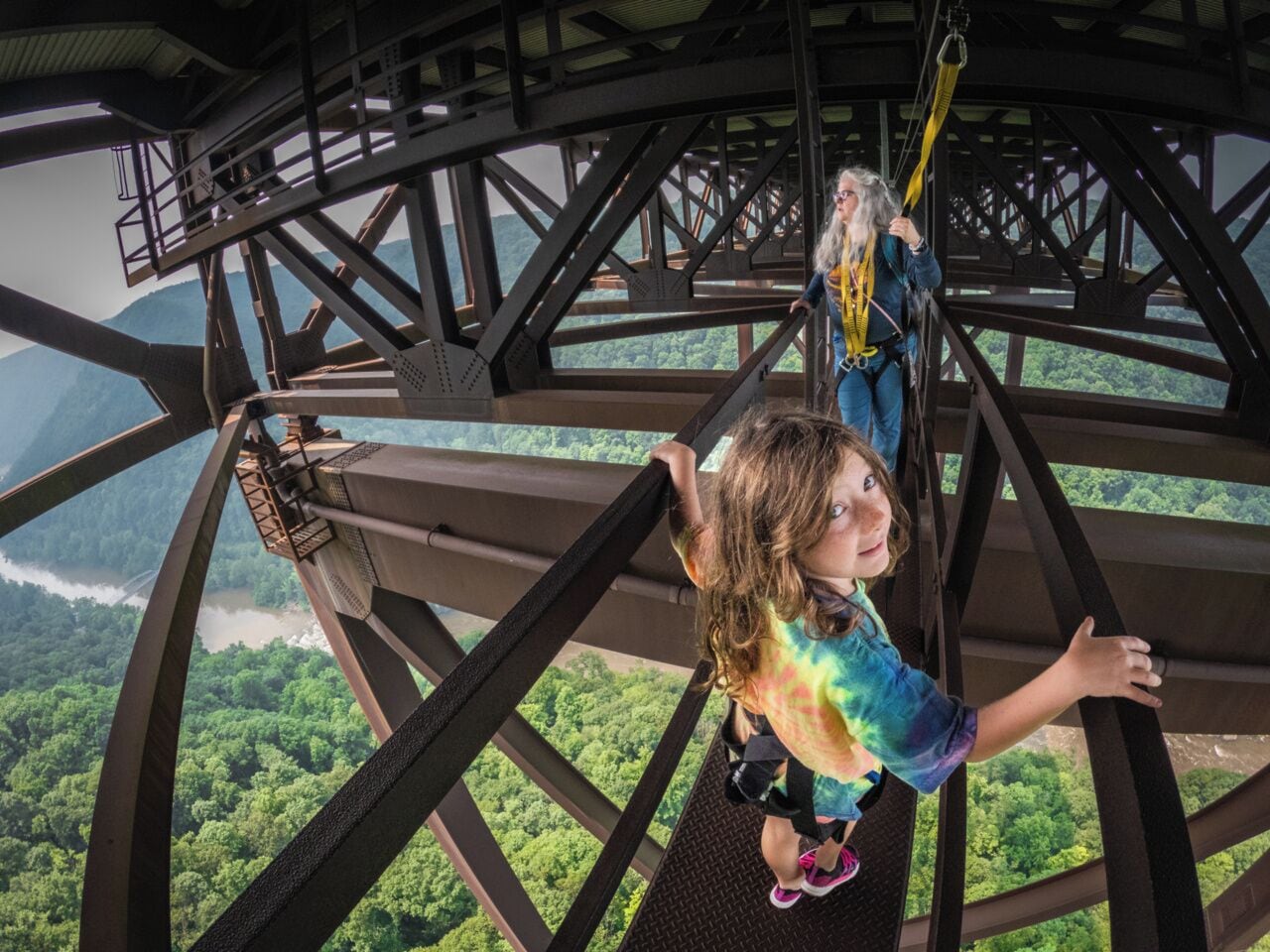 A person on a high platform with a view of a forested landscape below.