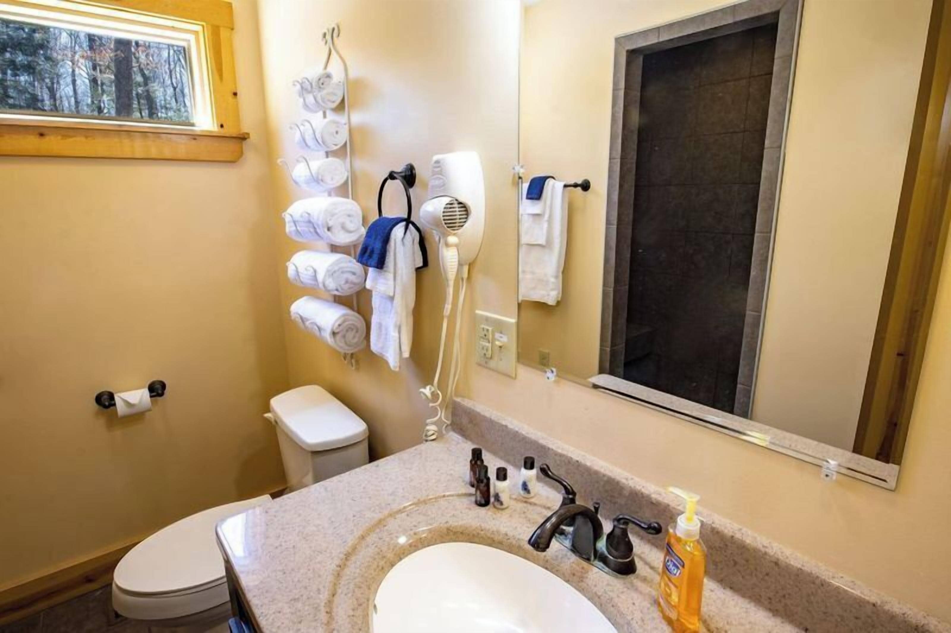 A bathroom with a sink, toilet, towel rack, and a mirror.