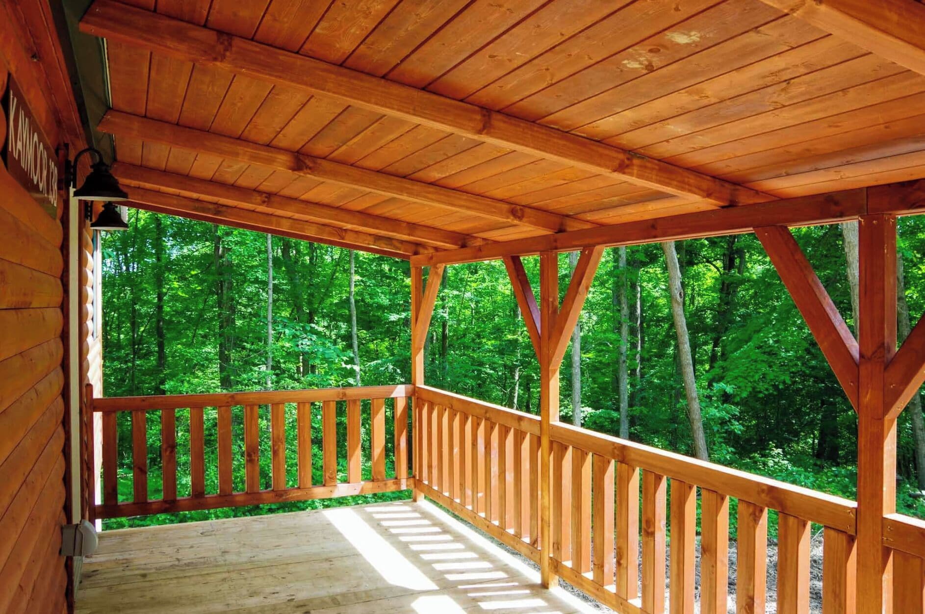 A wooden deck with a railing overlooking a forested area.