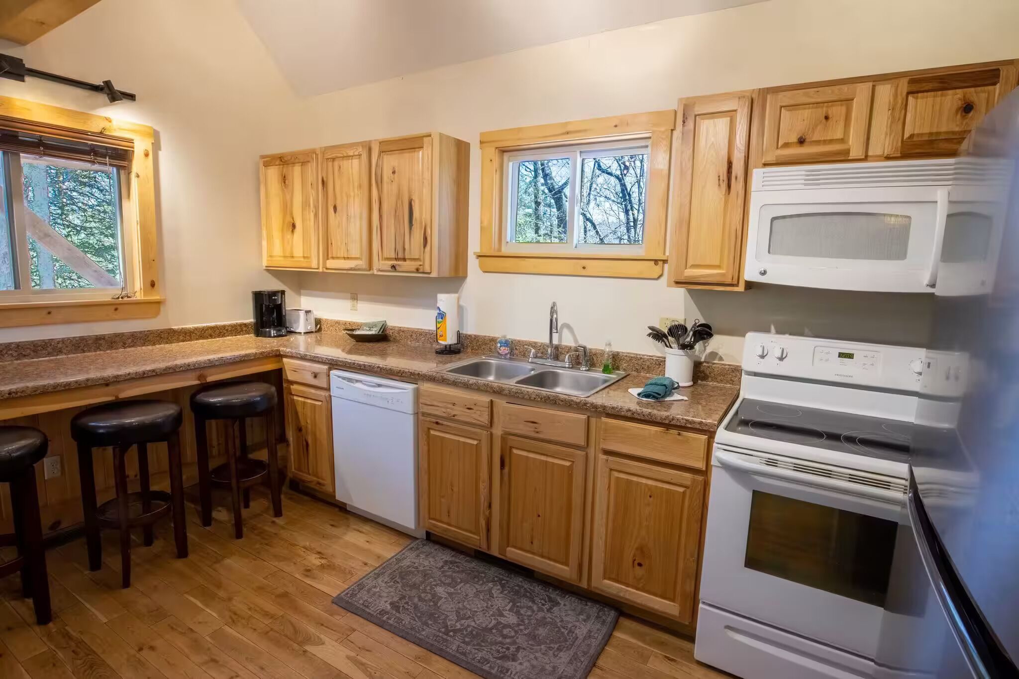Une cuisine avec des meubles de rangement en bois, un lave-vaisselle, une cuisinière et un évier.