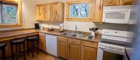 A kitchen with wooden cabinets, a dishwasher, a stove, and a sink.