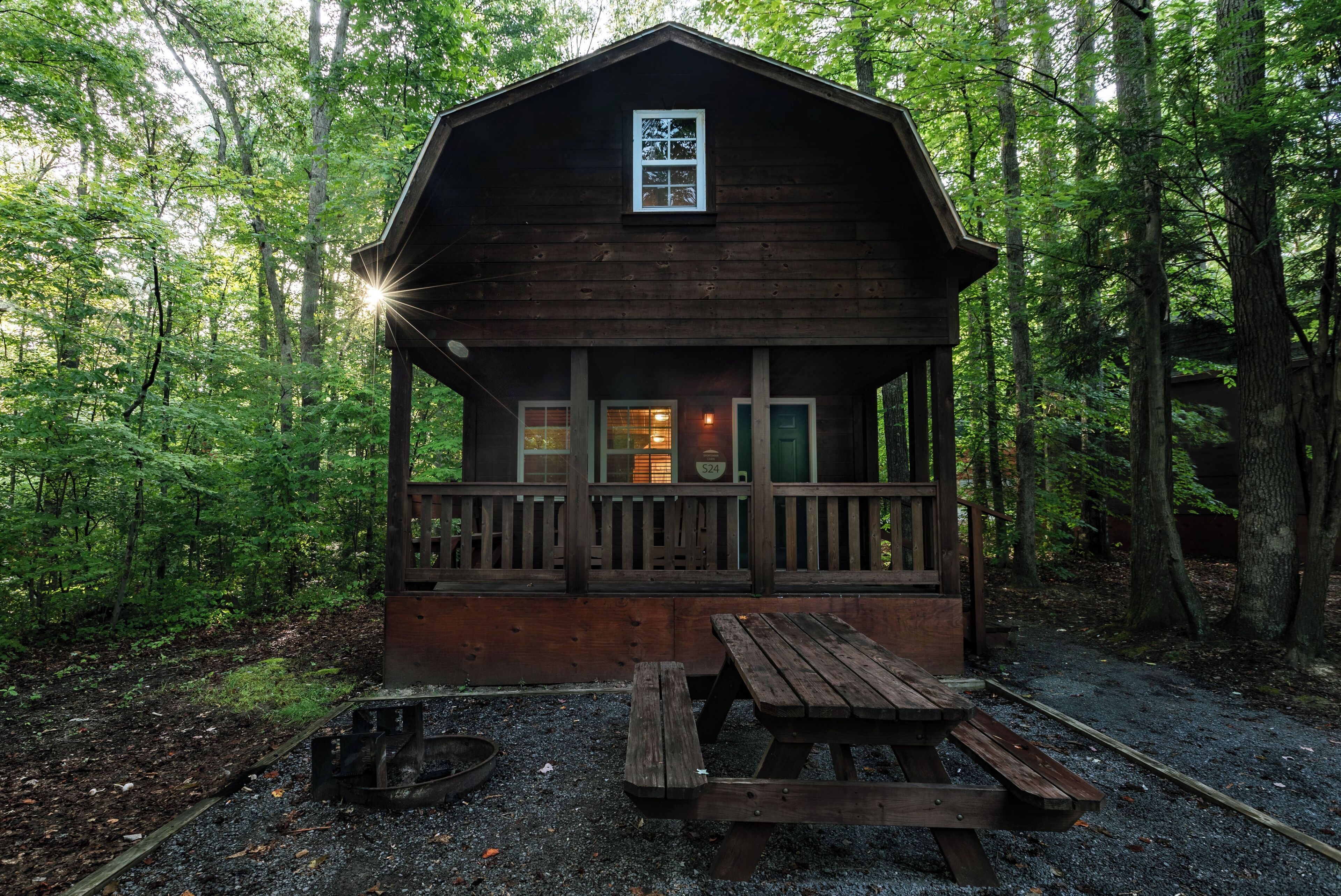 A wooden cabin with a porch, a picnic table, and a fire pit.