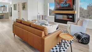 Un salon moderne avec un canapé en cuir, une cheminée et une grande fenêtre.