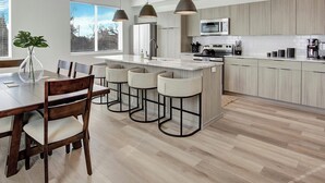 Une cuisine moderne dotée d’un îlot central, de tabourets de bar et d’une table à manger avec des chaises.