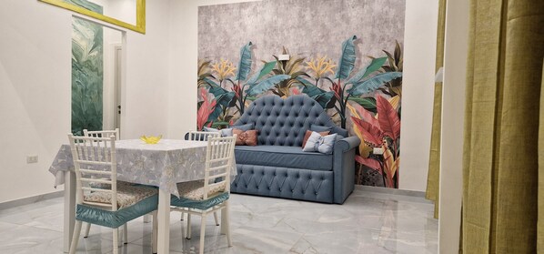 A dining area with a round table, white chairs, and a blue sofa.