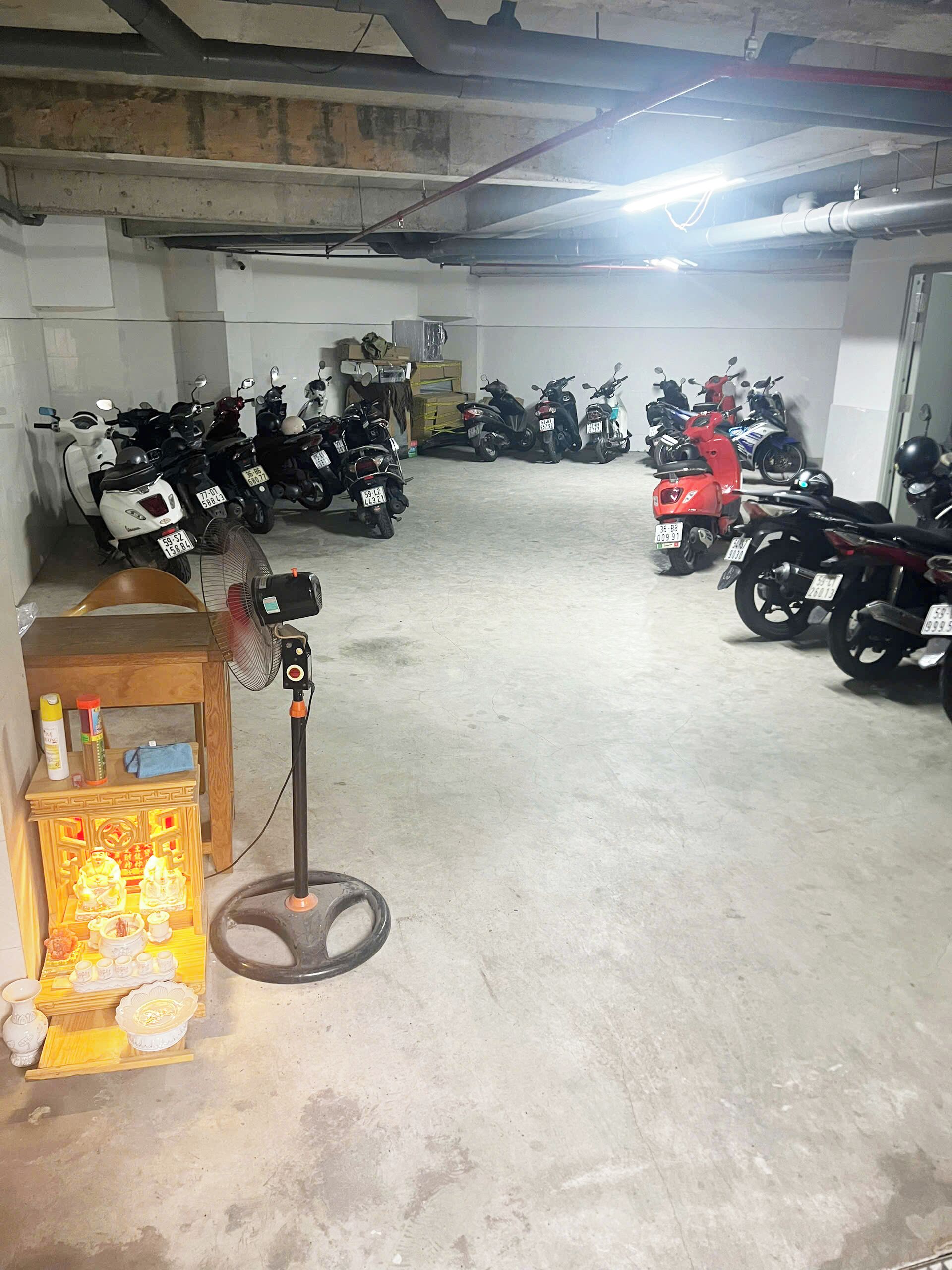 A parking garage with multiple scooters and motorcycles parked.