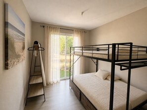 Habitación con literas, una escalera, un cuadro en la pared y una ventana con cortinas.