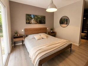 Ein Schlafzimmer mit einem großen Bett, einem Holz-Kopfteil, Nachttischen, einer Pendelleuchte und einem Bild an der Wand.