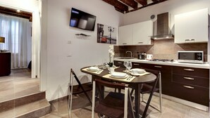 Una cocina moderna con armarios oscuros, un microondas y una zona de comedor con una mesa preparada para dos personas.