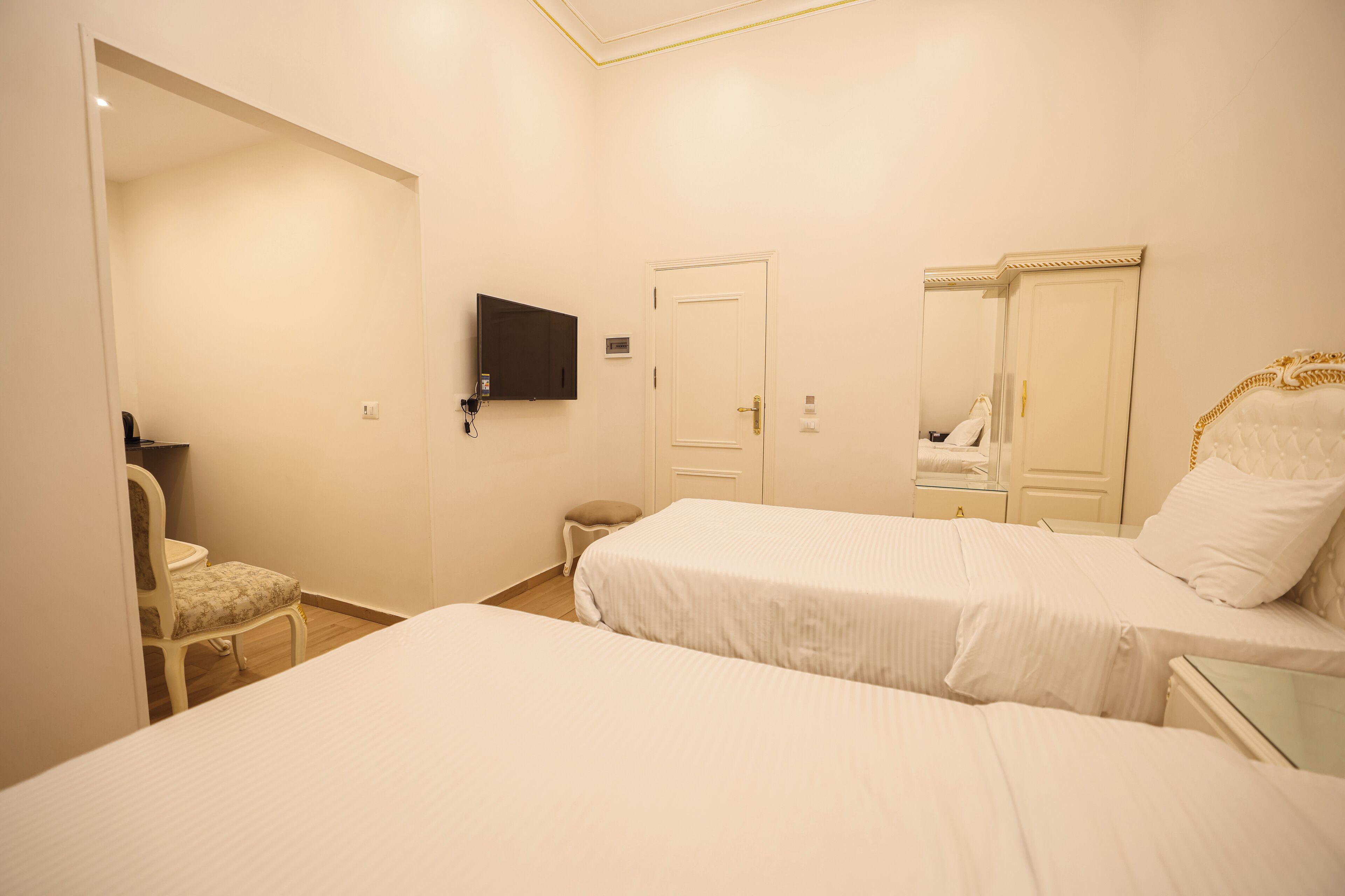 Ein Hotelzimmer mit zwei Betten, einem Fernseher, einem Sessel und einer Tür.
