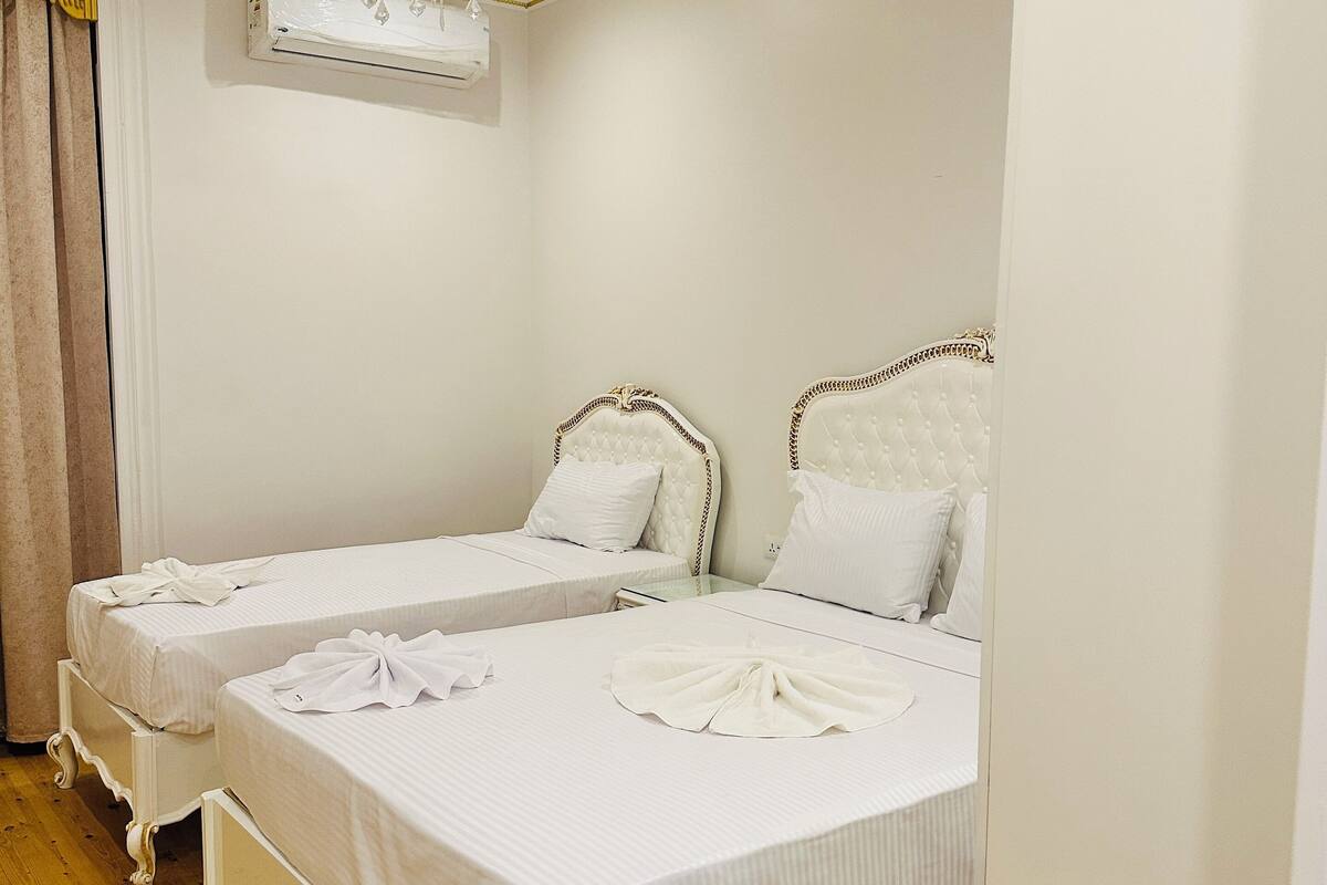 Une chambre d’hôtel avec deux lits, un lustre et un ventilateur de plafond.