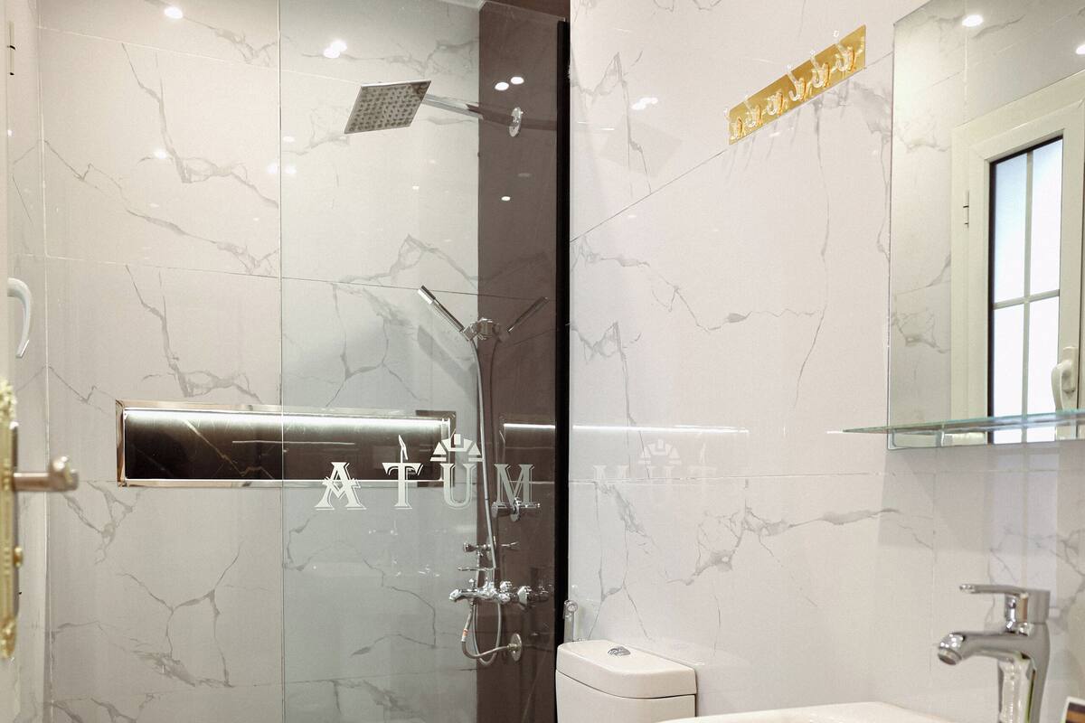 Une salle de bain moderne avec une douche à parois de verre, des toilettes blanches et un lavabo avec un miroir.