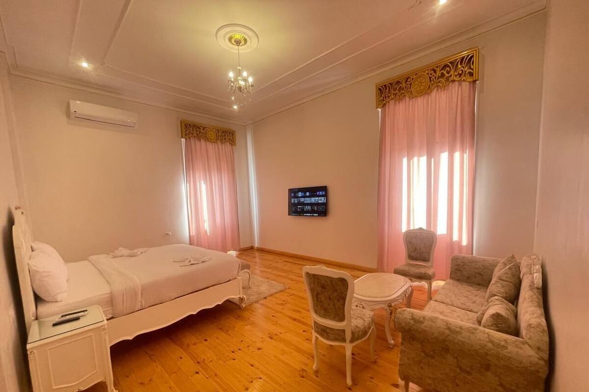 Une pièce comprenant un lit, un canapé, une chaise, une petite table et un téléviseur fixé au mur.