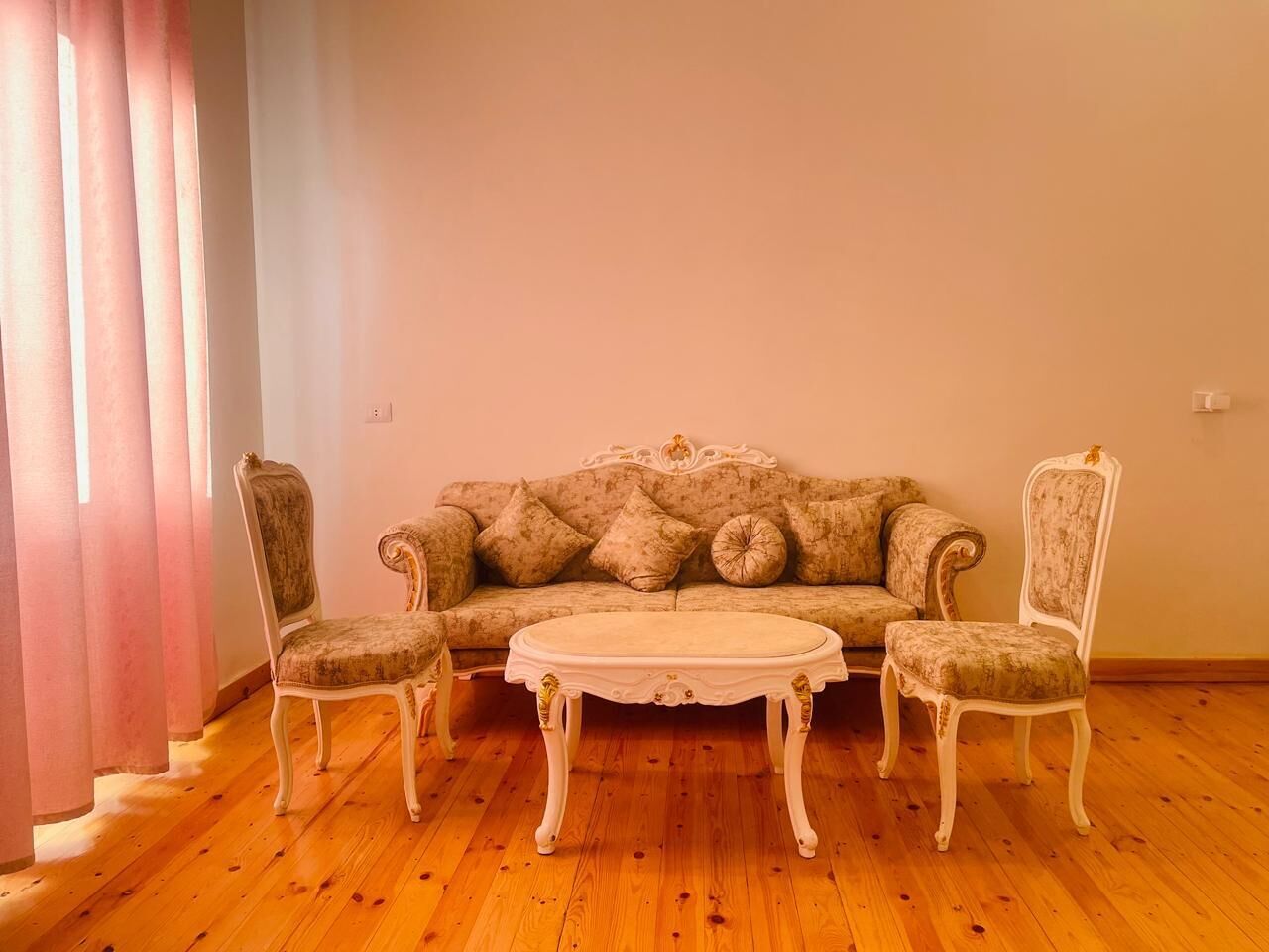 A room with a sofa, two armchairs, and a coffee table.