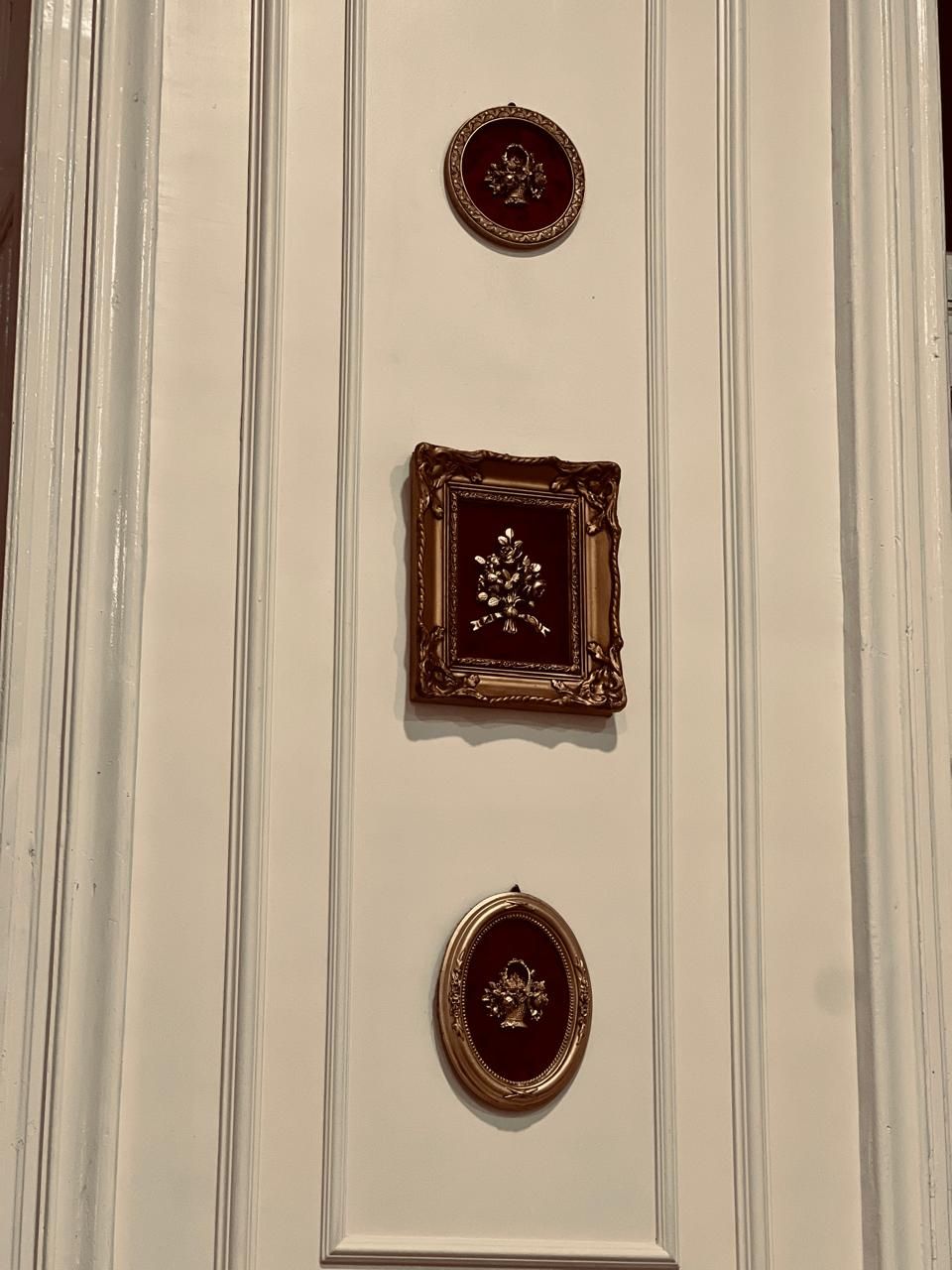 A wall with three decorative plaques, each with a different design, mounted in a vertical arrangement.