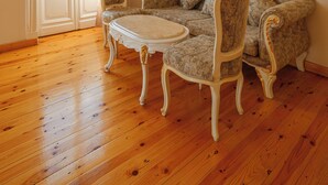 Een kamer met een houten vloer, een bank, twee fauteuils en een kleine tafel.