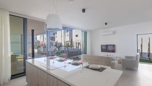 Una cocina moderna con una isla grande, un comedor con sofá y un televisor en la sala.