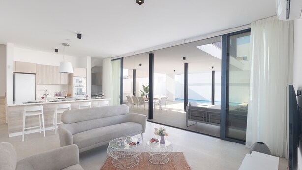 Una sala moderna con sofá, mesa de centro y vistas a la cocina y un balcón.