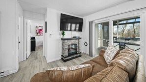 Uma sala de estar moderna com lareira, um sofá e uma TV fixada na parede.