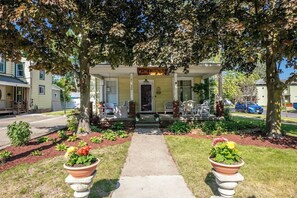 A two-story house with a porch, a sign reading 'WINE COUNTRY,' and a pathway leading to the entrance. - Your Group's Home Base | Downtown | Hot Tub+Games (Watkins Glen)