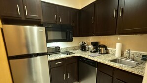 A modern kitchen with dark cabinets, stainless steel appliances, a microwave, toaster, coffee maker, and a dishwasher.