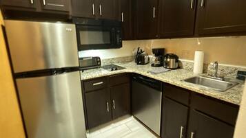 A modern kitchen with dark cabinets, stainless steel appliances, a microwave, toaster, coffee maker, and a dishwasher.