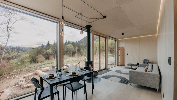 Um interior moderno com área de jantar, sofá e uma grande janela com vista para o exterior.