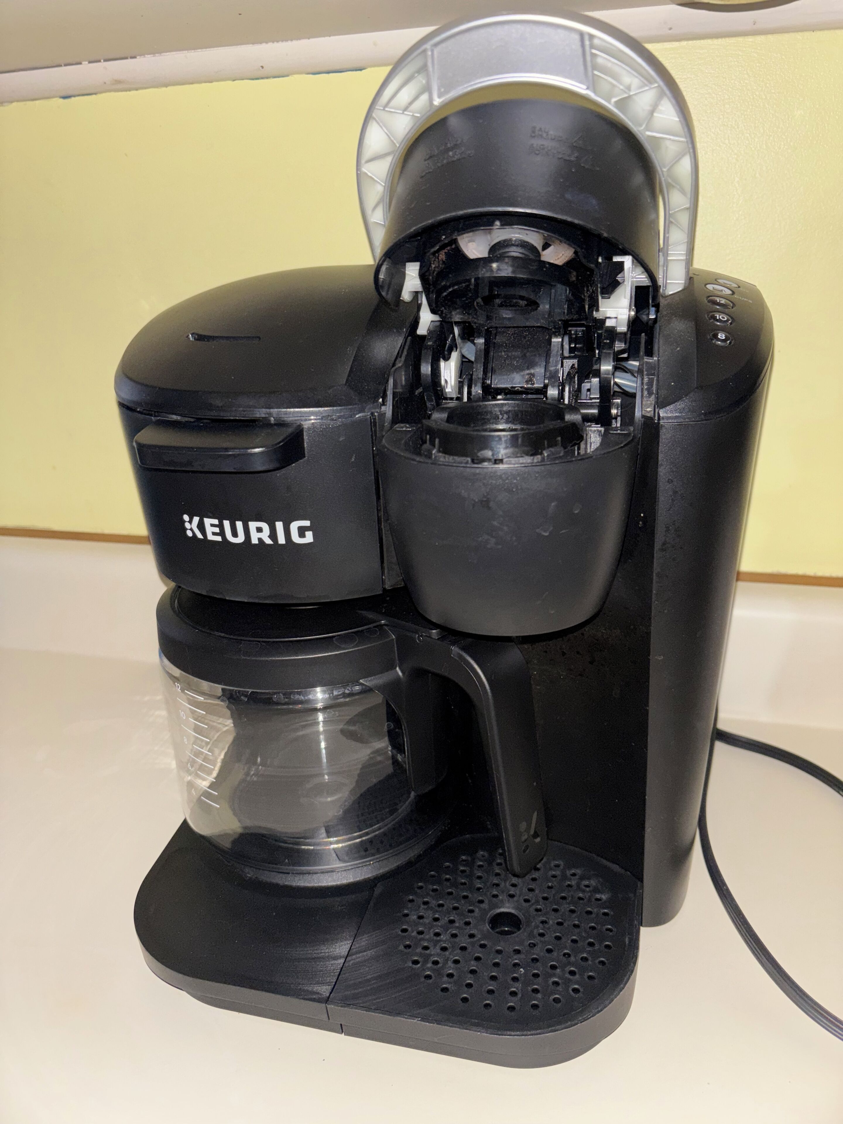 Een zwarte Keurig koffiezetapparaat met een transparante waterreservoir en een drip tray.
