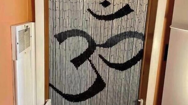 Kapea käytävä, jonka seinässä on pystysuorassa oleva bambupaneeli, ja siinä on suuri musta Om-symboli.